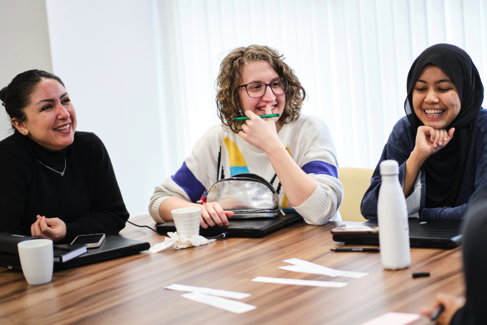 Group of female researchers laughing together, sat at a desk