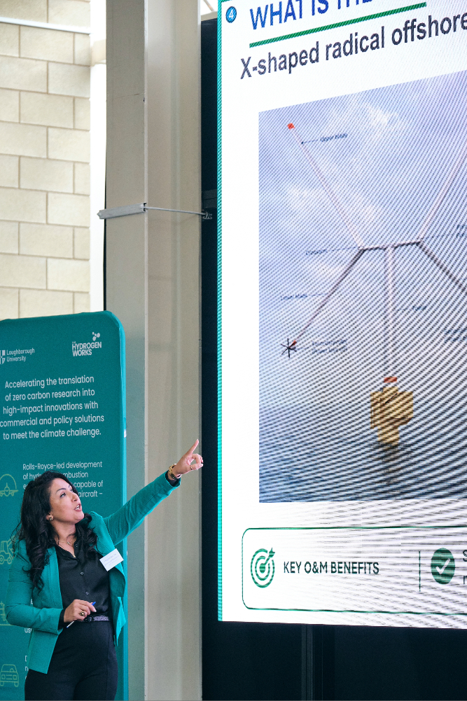 Female researcher presents work on the innovative X-Rotor offshore wind turbine design, large screen in background