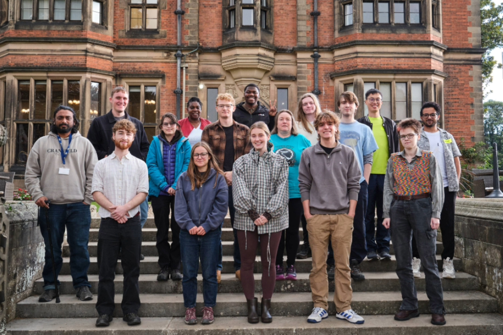 Diverse group of researchers standing on steps outside an old manor house