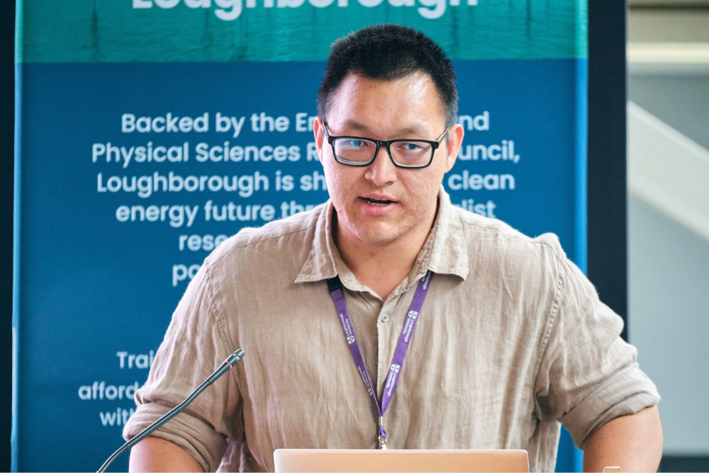 Male researcher presenting at lectern, banner in background
